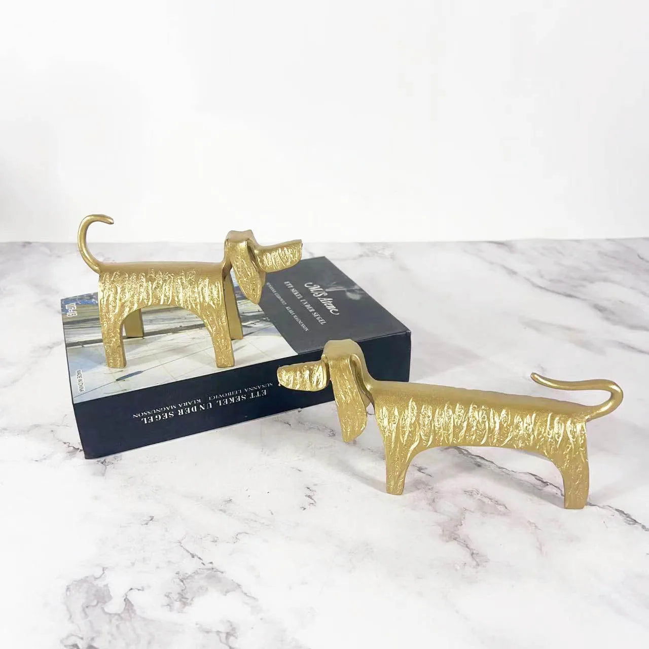 Gold dog-shaped objects on a marble surface with a box in the background