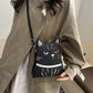 Person holding a black cat-shaped handbag with a plain background