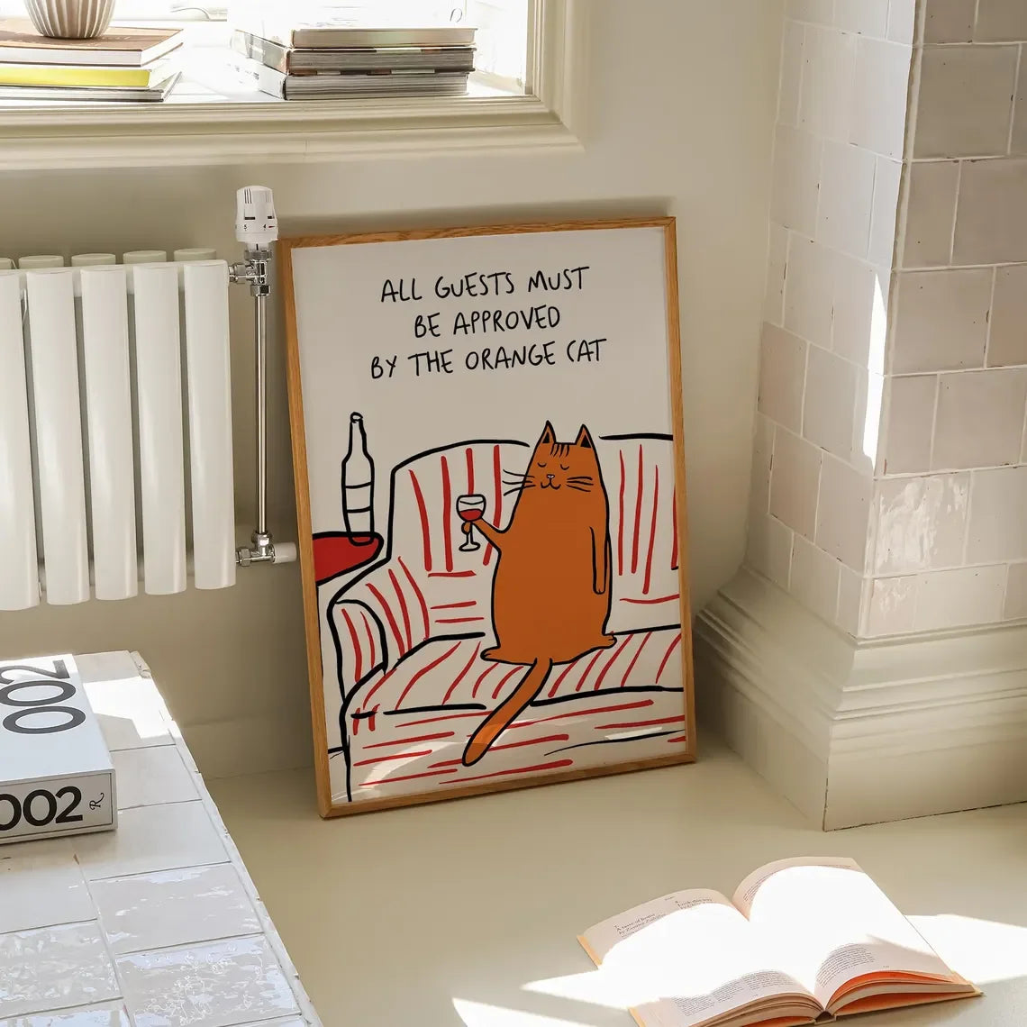 Framed artwork with a cat illustration and text on a wall in a room.