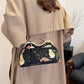 Person wearing a beige coat holding an embroidered handbag with floral designs.