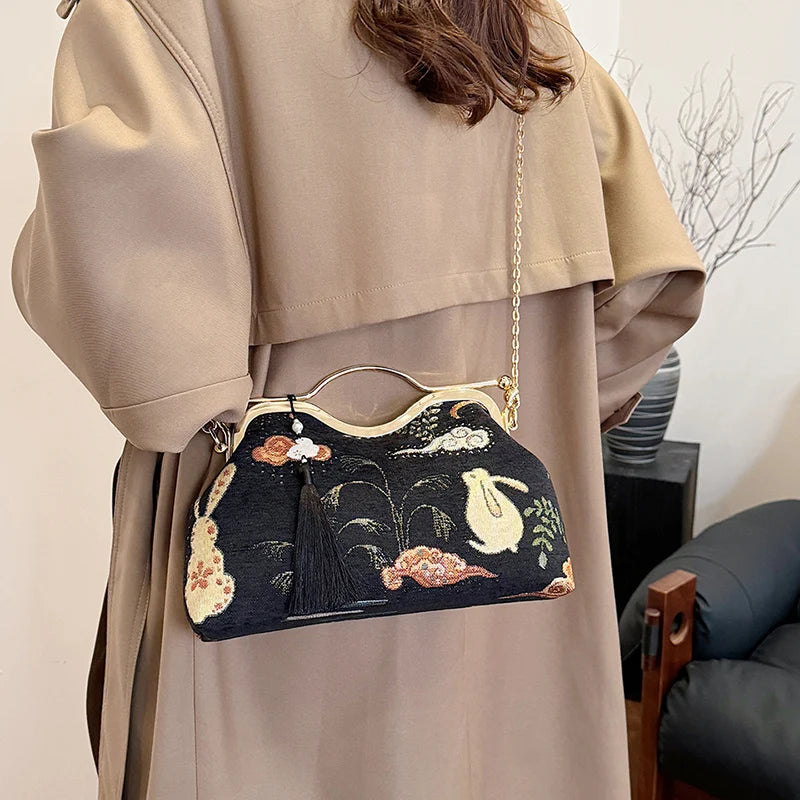 Person wearing a beige coat holding an embroidered handbag with floral designs.
