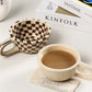 Checkered mug, coffee cup, and 'KINFOLK' magazine on a white surface with 'zizi fish' branding.