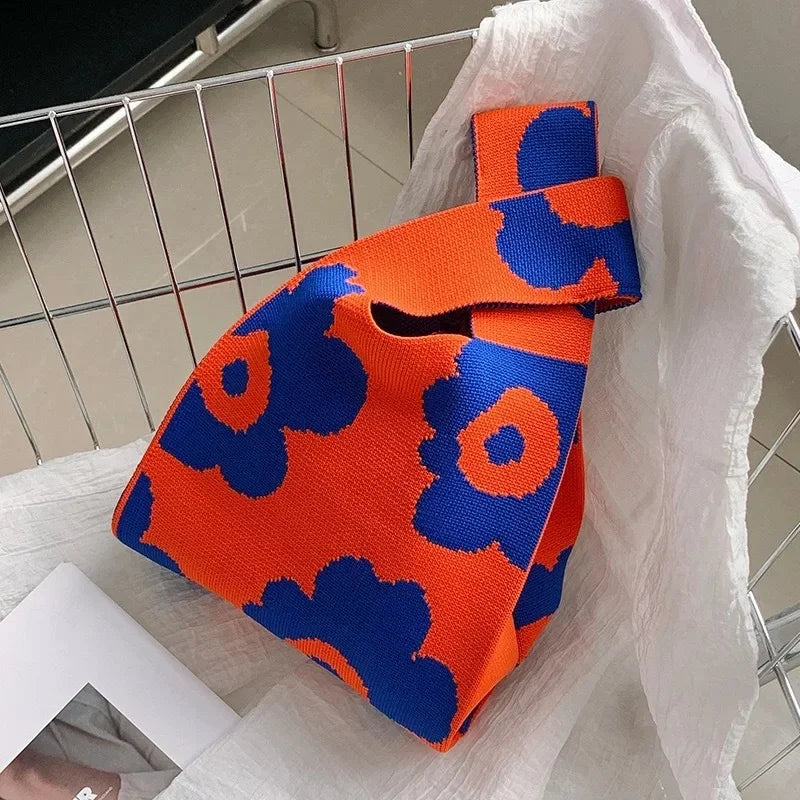 Orange and blue patterned bag on a white surface with a metal rack in the background