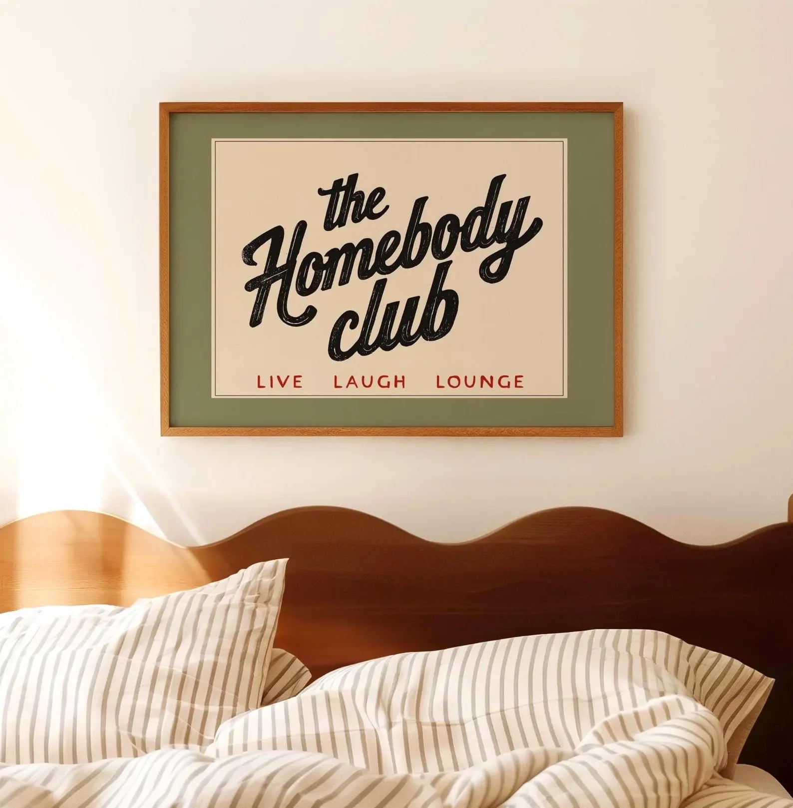 Framed artwork with 'the Homebody Club' text above a bed.