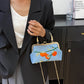 Person holding a blue handbag with floral design in an indoor setting