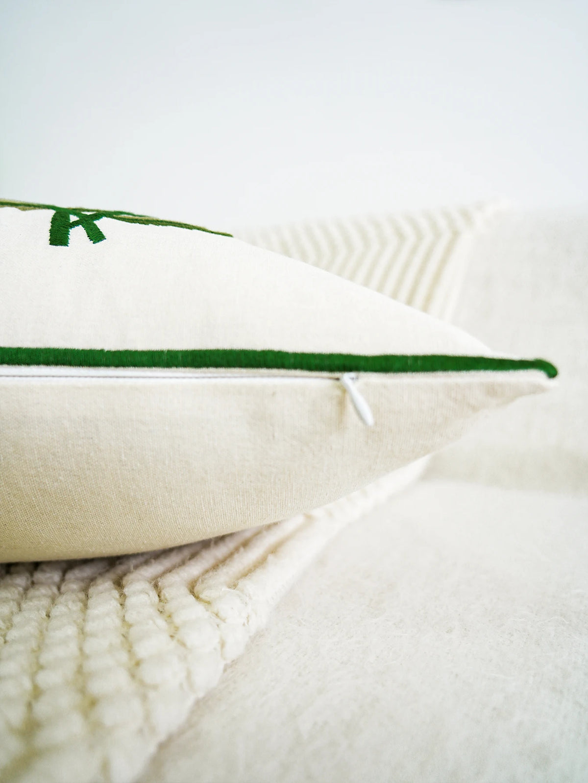 Close-up of a white pillow with green stitching on a white background