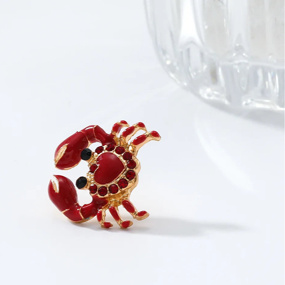 Red and gold lobster-shaped brooch on a white background