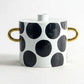 Ceramic pot with black polka dots and gold handles, shown with measurements on a white background.