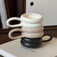 Stacked ceramic mugs in white, beige, and black on a book