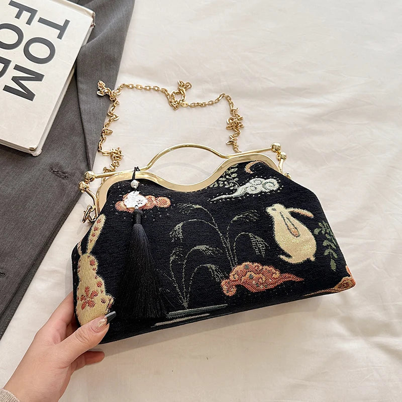 Black embroidered handbag with floral designs held by a hand on a light background