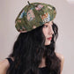 Woman wearing a patterned beret against a plain background
