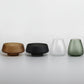 Four glass containers of different colors and sizes on a white background