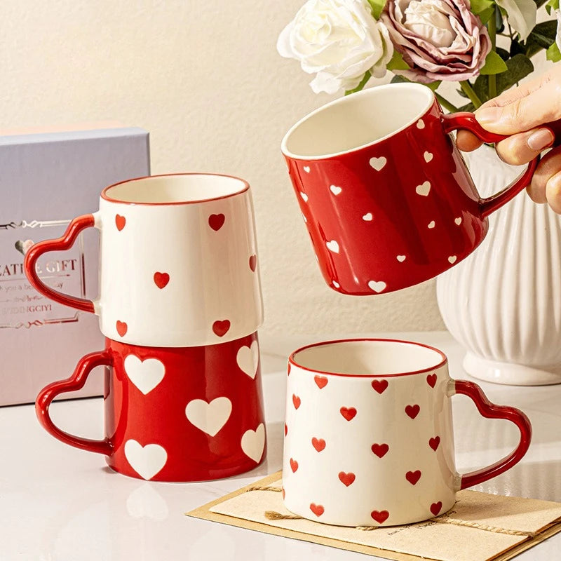Set of red and white heart-patterned mugs on a surface with a decorative background.