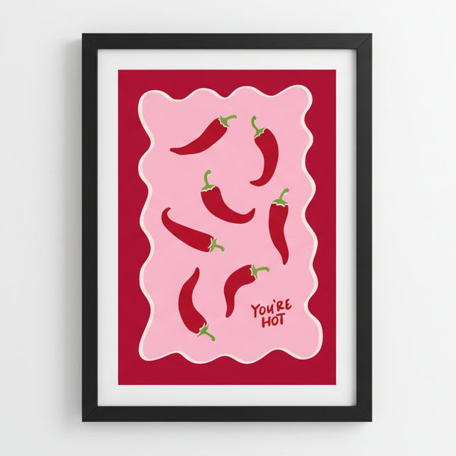 Framed artwork with red peppers and 'You're Hot' text on a red background