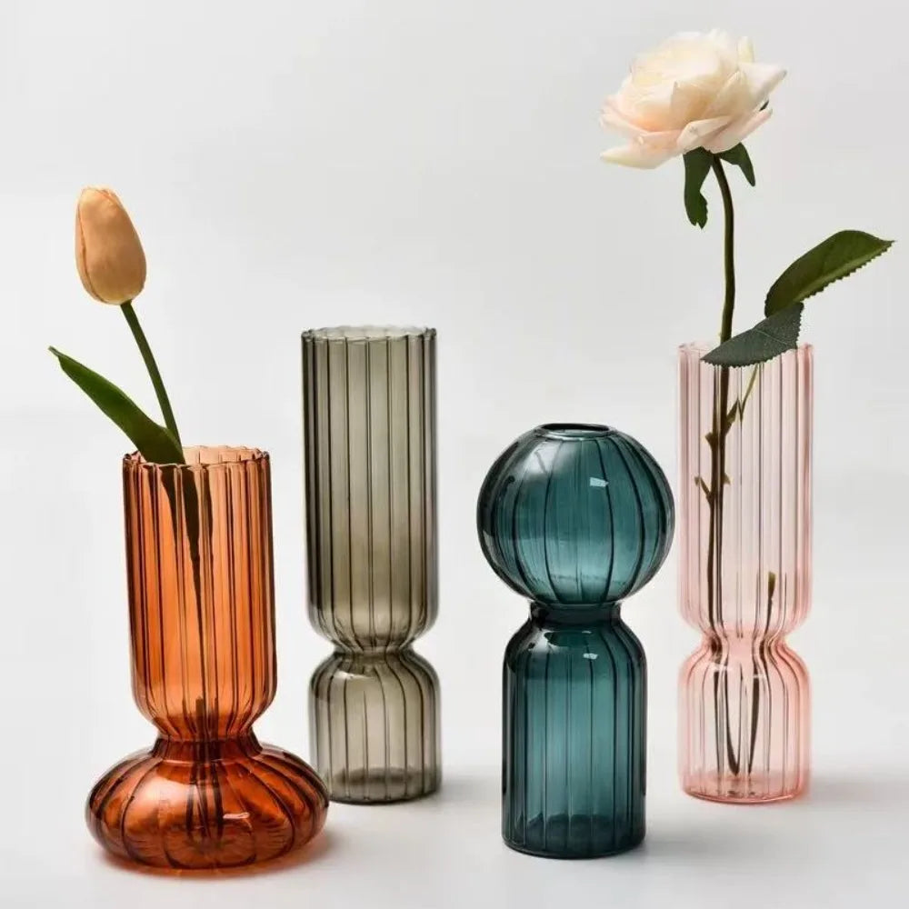 Four colorful glass vases with flowers on a light gray background