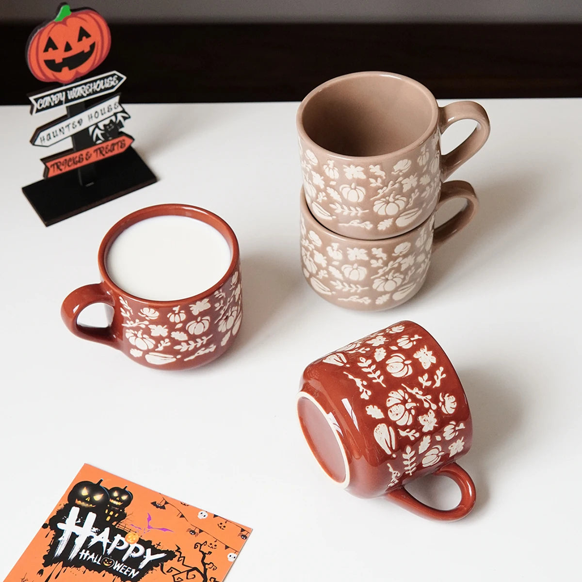 Set of Halloween-themed mugs on a white surface with decorative signs.
