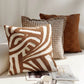 Three patterned pillows on a white sofa with a magazine and cup.