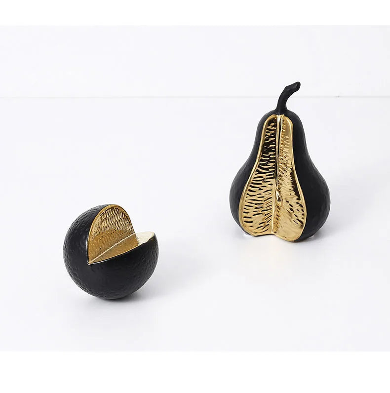 Two decorative pears with gold and black finishes on a white background