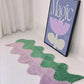 Wavy purple and green rug on a light floor with a framed picture of a flower and 'Magic' text in the background.