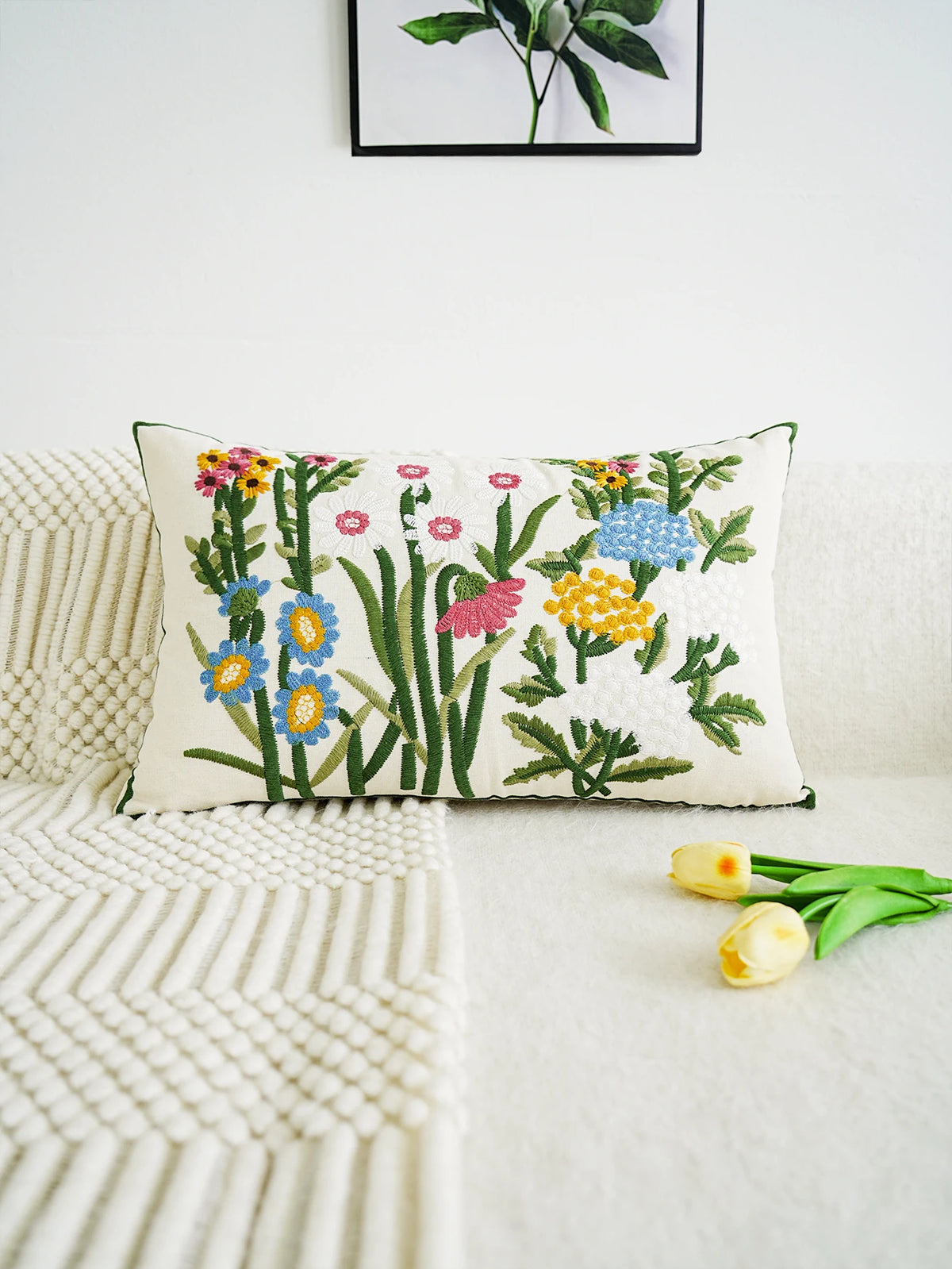 Decorative pillow with floral embroidery on a white couch with tulips.