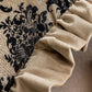Close-up of beige ruffled fabric against a black floral patterned background