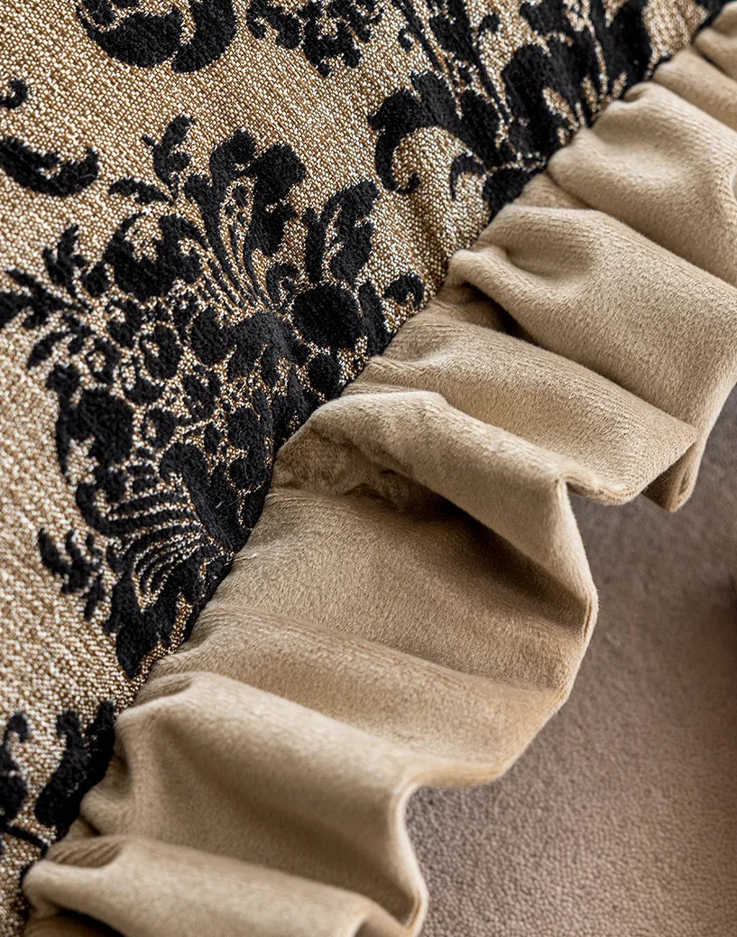 Close-up of beige ruffled fabric against a black floral patterned background
