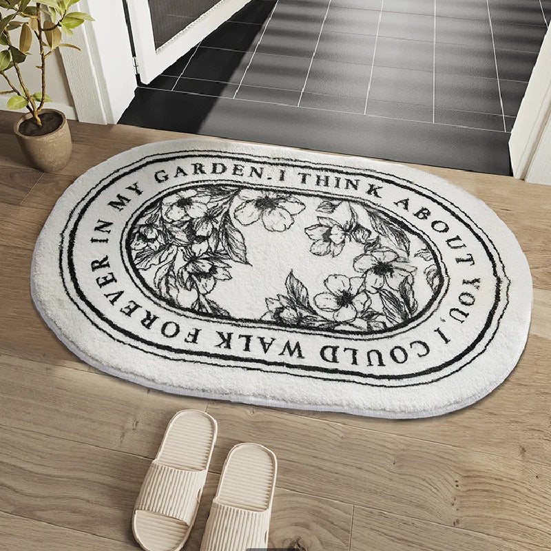 Decorative doormat with floral design and text on a wooden floor.