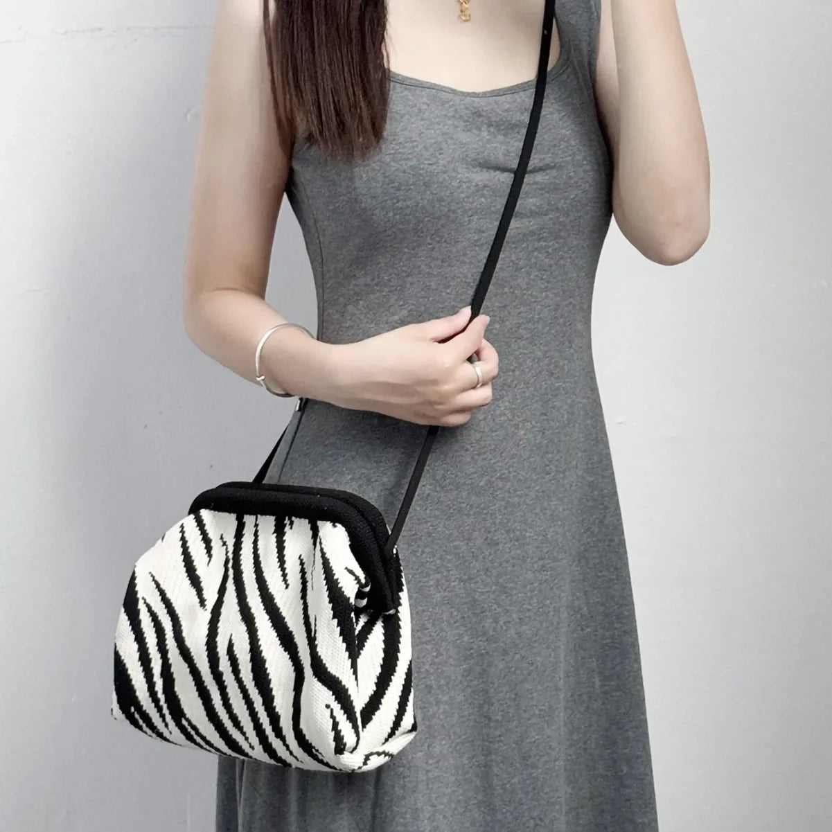 Person holding a zebra patterned handbag against a plain background