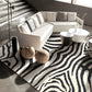 Modern living room with a zebra-patterned rug, white sofa, and decorative items.