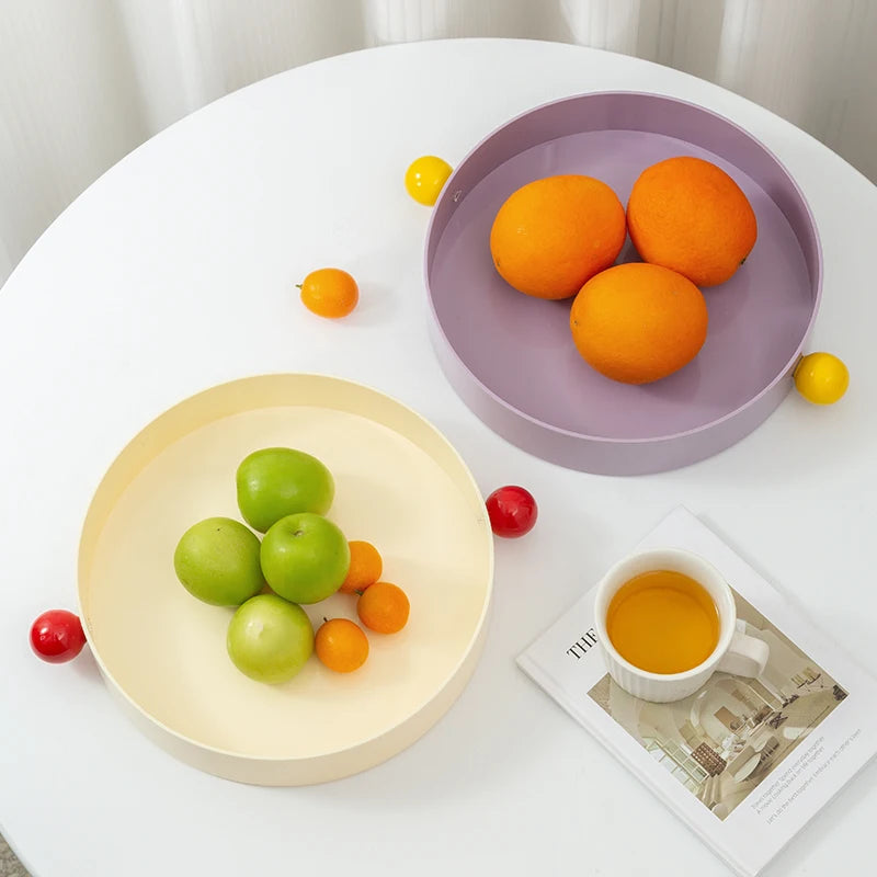 Fruit on two plates with a cup of tea and newspaper on a white table.
