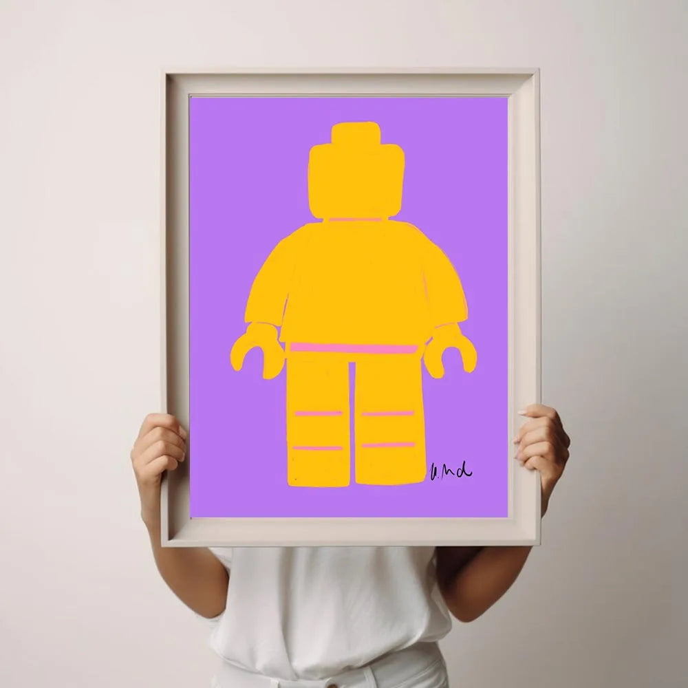 Person holding a framed print of a yellow Lego figure on a purple background