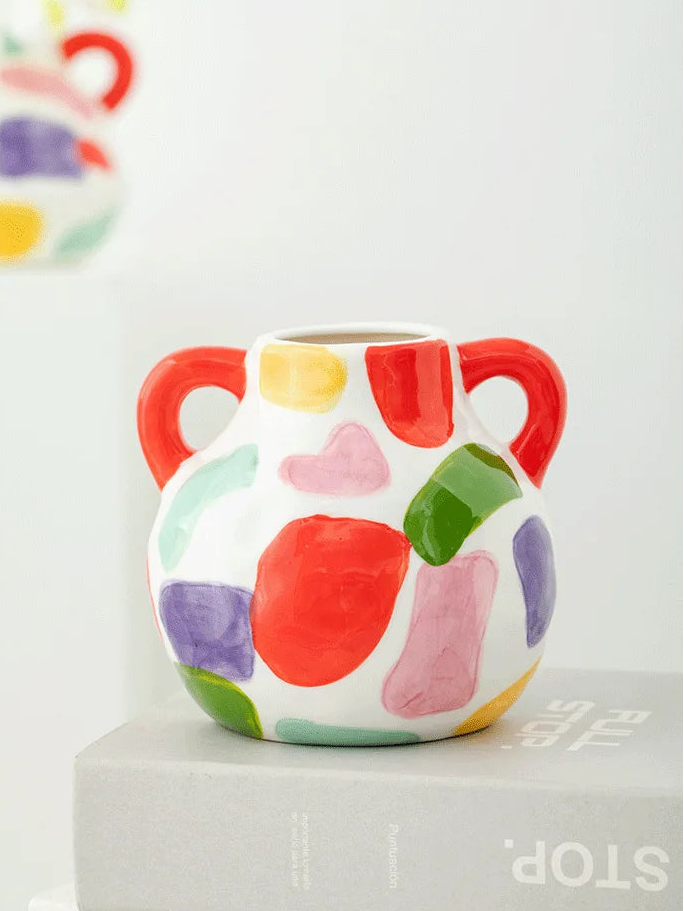 Colorful ceramic vase with abstract patterns on a white surface