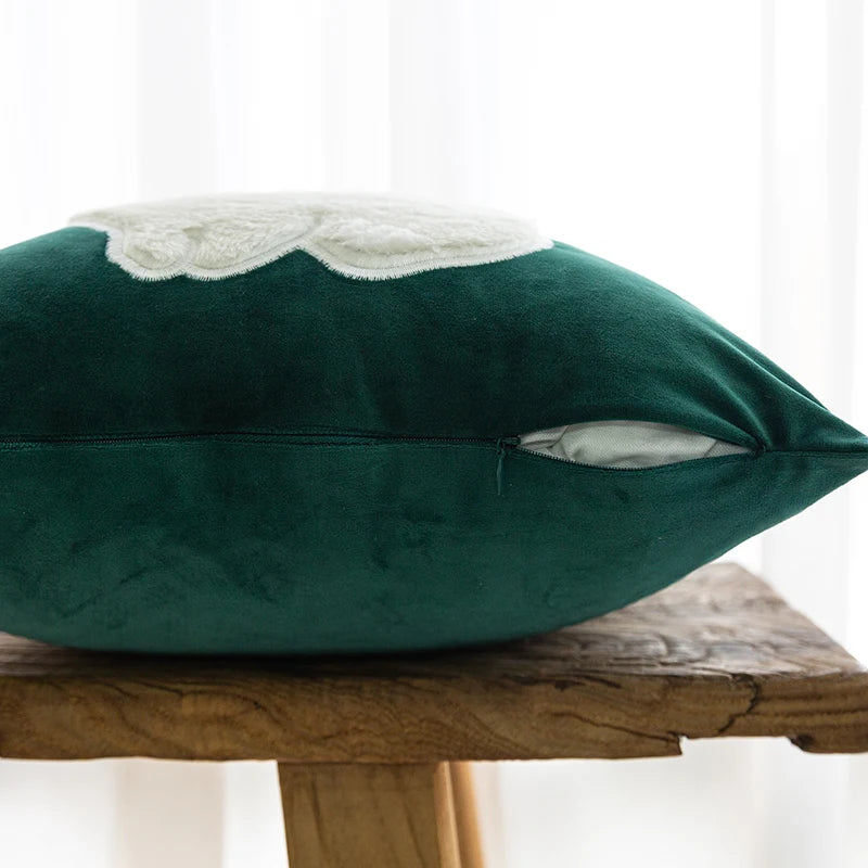 Green velvet pillow with lace trim on a wooden surface