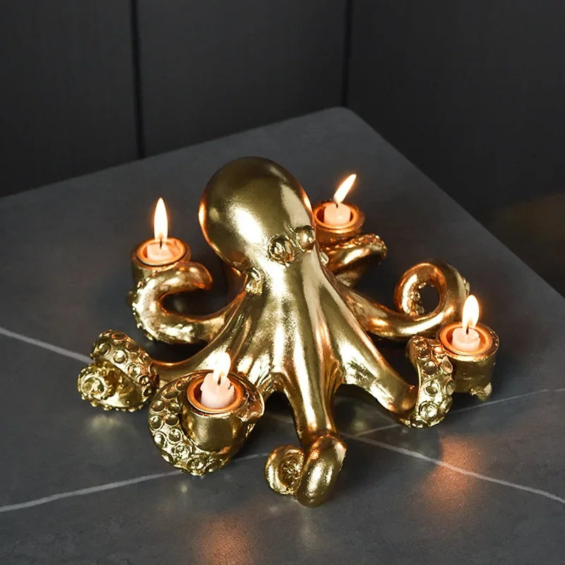 Gold octopus candle holder with four lit candles on a dark surface