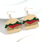 Burger-shaped earrings on a white background