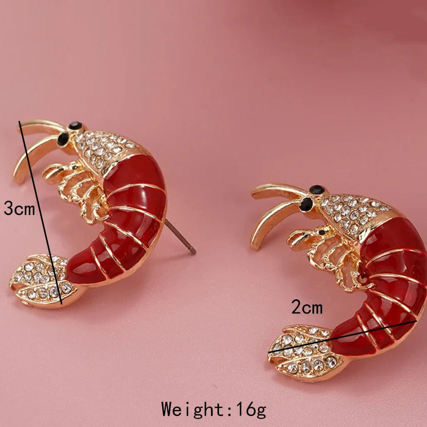 Shrimp-shaped earrings with measurements and weight on a pink background