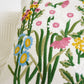 Embroidered floral design on a pillow with colorful flowers and green leaves.