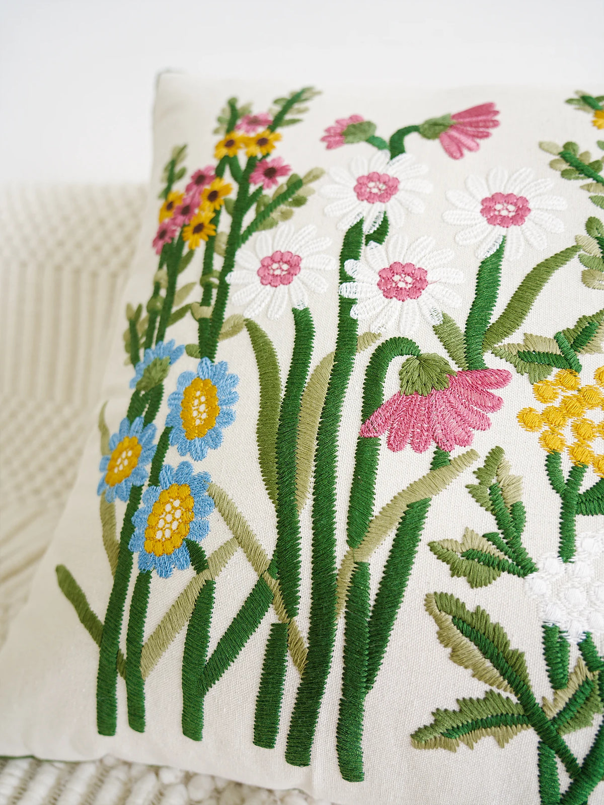 Embroidered floral design on a pillow with colorful flowers and green leaves.