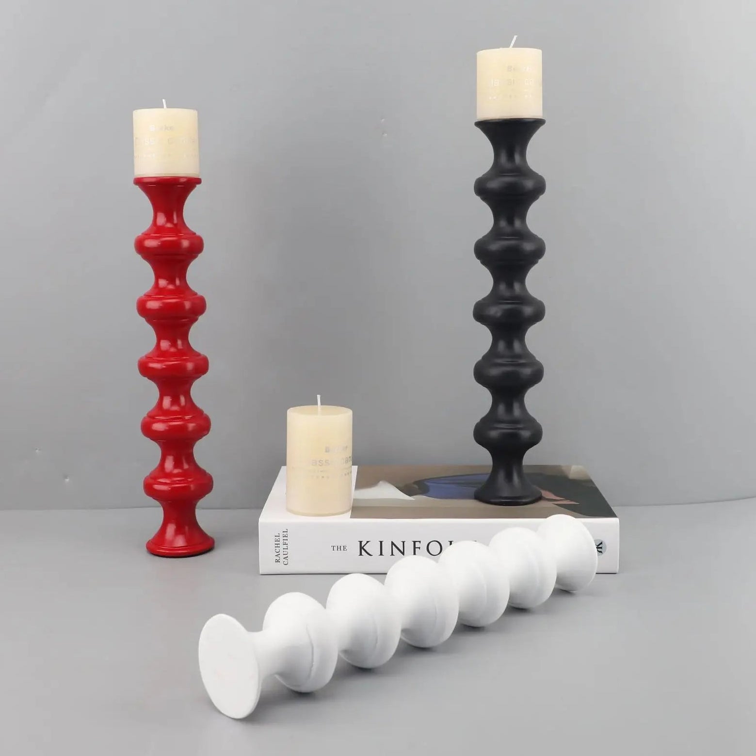 Red, black, and white candle holders with candles on a gray surface and background.
