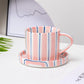 Striped ceramic mug and coaster set on a light surface with a blurred background