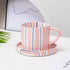 Striped ceramic mug and coaster set on a light surface with a blurred background