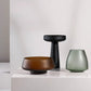 Three decorative vases in brown, black, and green on a white surface with a light gray background