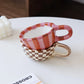Two ceramic cups stacked on a white surface with a blurred background