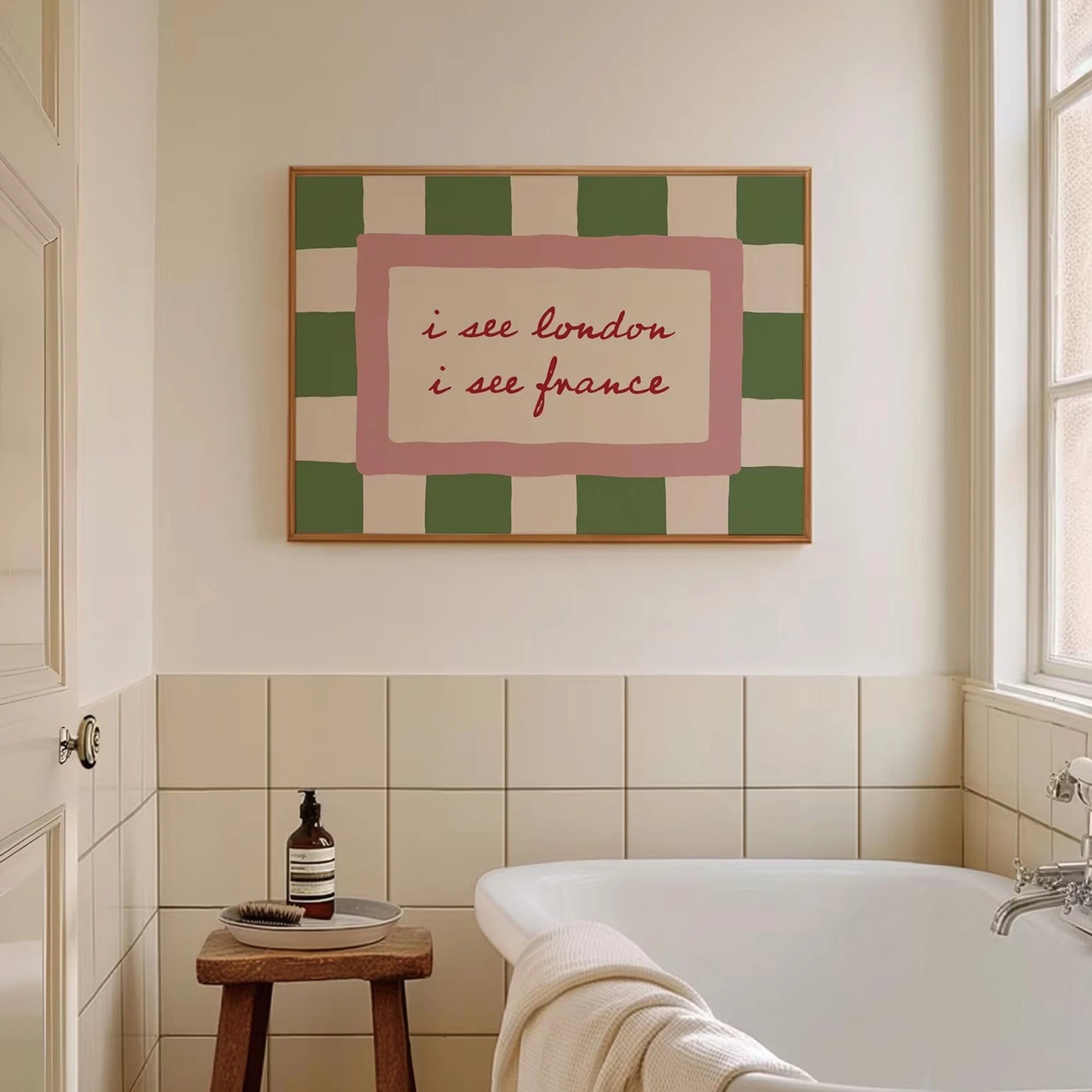 Bathroom with a bathtub, stool, and framed artwork on the wall.