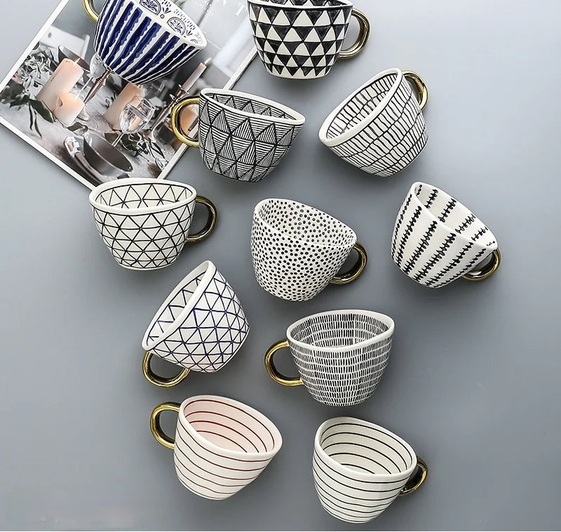 Collection of ceramic cups with various geometric patterns on a gray surface.
