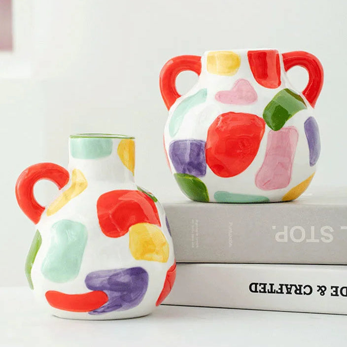 Two colorful ceramic vases with abstract patterns on a white surface.