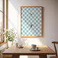 Framed checkered artwork above a wooden table with coffee cups and a vase.