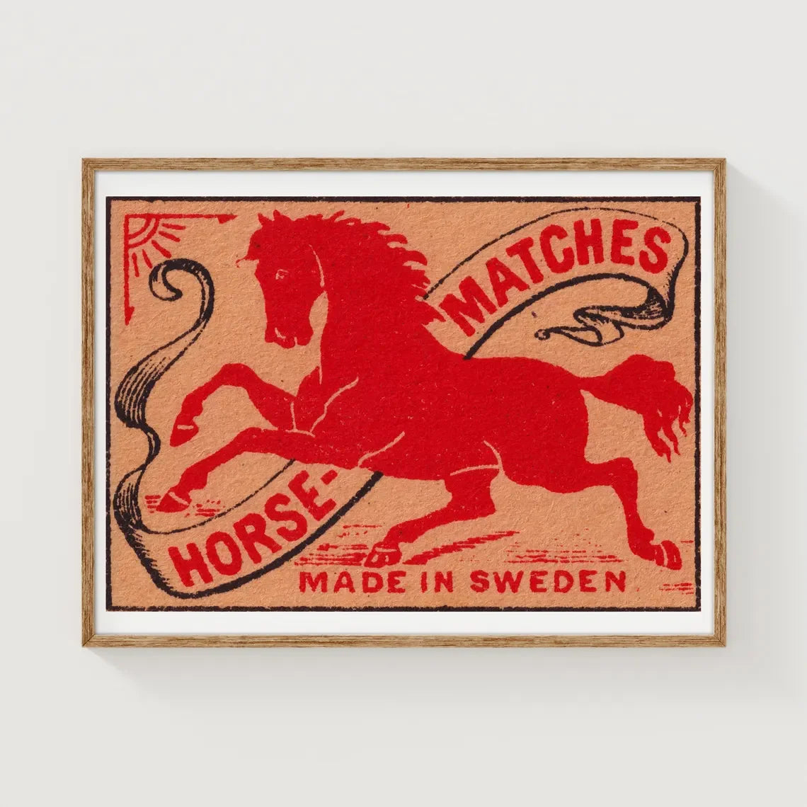 Framed matchbox label with a red horse design and text on a white background
