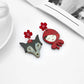 Pair of earrings with a red hooded character and flower details on a white surface.