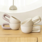 Set of white and pink ceramic bowls on a wooden surface with a neutral background
